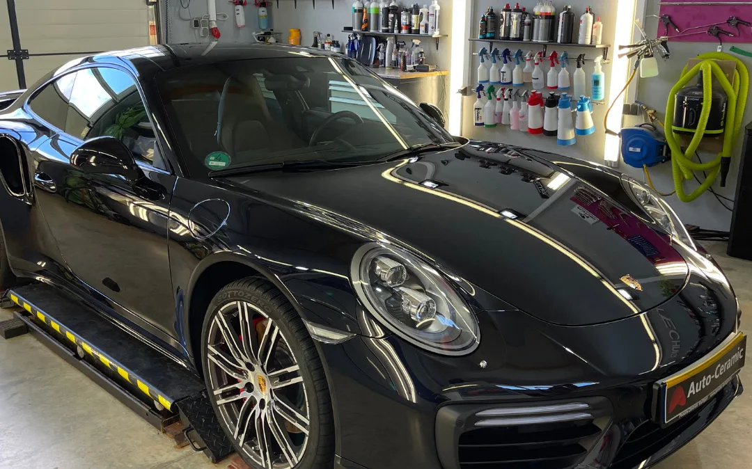 Schwarzer Porsche 911 Turbo mit spiegelnder Motorhaube in der Werkstatt