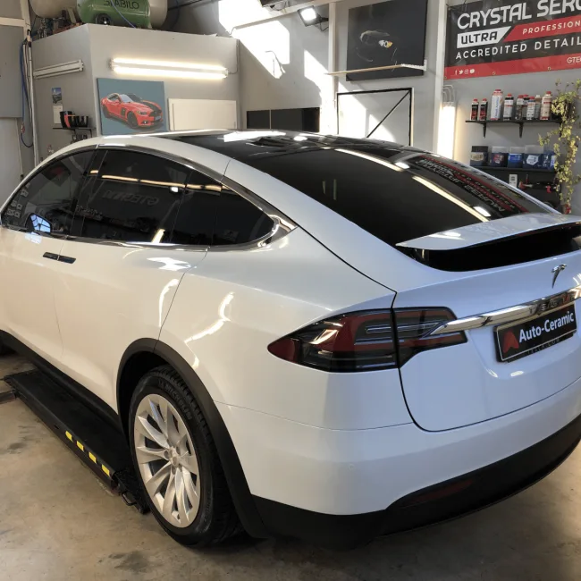 Weißes Tesla Model X mit getönten Scheiben in der Werkstatt