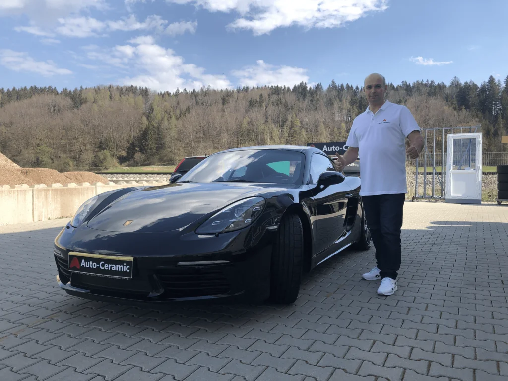 Sergej Gossen, Inhaber von Autopflege Kaufbeuren, neben einem frisch aufbereiteten Porsche 718 vor der Werkstatt